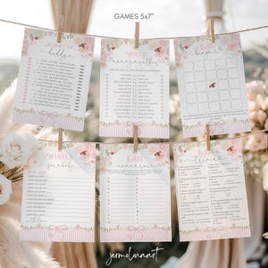 以下が含まれることがあります： 「Mommy or Daddy」「Would the Mother」「Baby Bingo」「Wishes for Baby」「Baby Name Race」「Baby Trivia」など、ベビーシャワーゲームのコレクション。カードは12.7 x 17.8 cmで、花柄とピンクのストライプのデザインです。