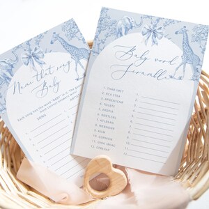 K&ouml;nnte beinhalten: Zwei blaue und wei&szlig;e Babyparty-Spielkarten mit einem Giraffen- und Elefanten-Design. Die erste Karte ist mit "Name that song Baby" betitelt und die zweite Karte mit "Baby Word Scramble".