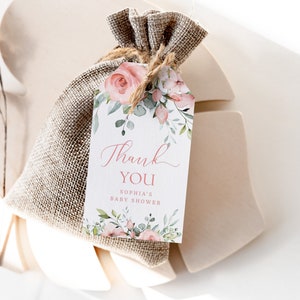 May include: A white thank you tag with pink floral illustrations and the text "Thank You Sophia's Baby Shower". The tag is tied to a small burlap bag.