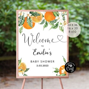May include: A welcome sign for a baby shower with a watercolour illustration of orange blossoms and oranges. The sign says "Welcome to Emilia's Baby Shower 3.03.2023".