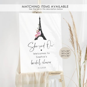 May include: A printable bridal shower sign with a black and white illustration of the Eiffel Tower with pink flowers. The text reads "She said "Oui" Welcomes to Sophia's bridal shower 3.3.2025 @jermolinaart 16"x 20" 18"x 24" 24"x 36"