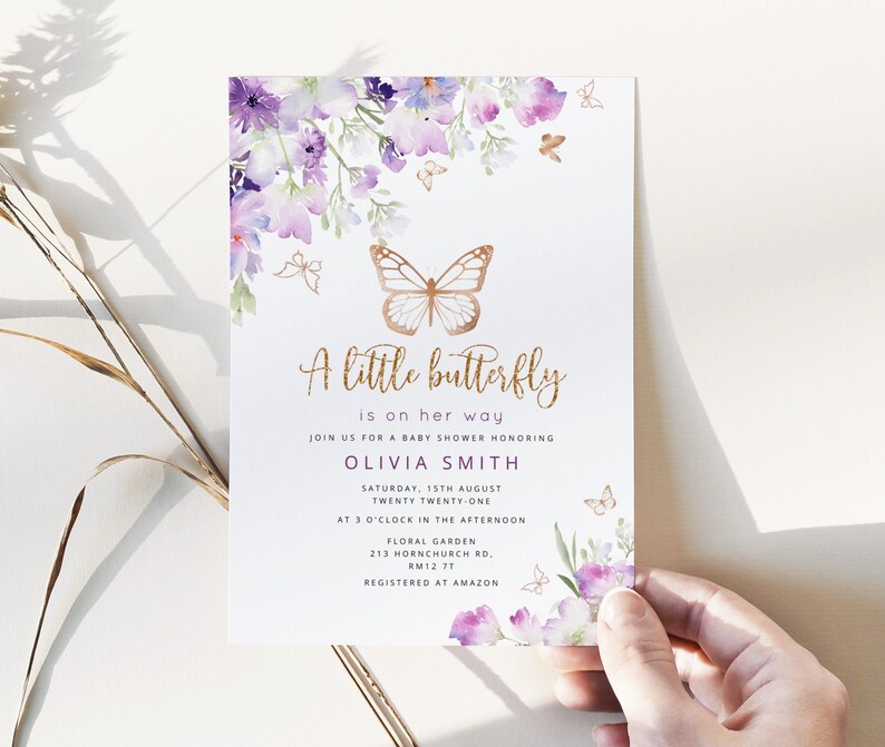 Może przedstawiać: Zaproszenie na baby shower z akwarelowym wzorem kwiatowym w odcieniach fioletu i błękitu. Zaproszenie zawiera złotego motyla i tekst "A little butterfly is on her way." Zaproszenie jest dla Olivii Smith i zawiera datę, godzinę i miejsce imprezy. Tekst "Registered at Amazon" r&oacute;wnież jest uwzględniony.