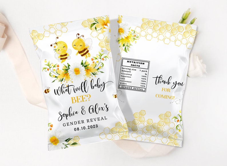 May include: A white favor bag with a honeycomb pattern and yellow flowers. The bag has text that says "What will baby BEE? Sophia & Alex's Gender Reveal 08.10.2023". There are two cartoon bees on the bag.