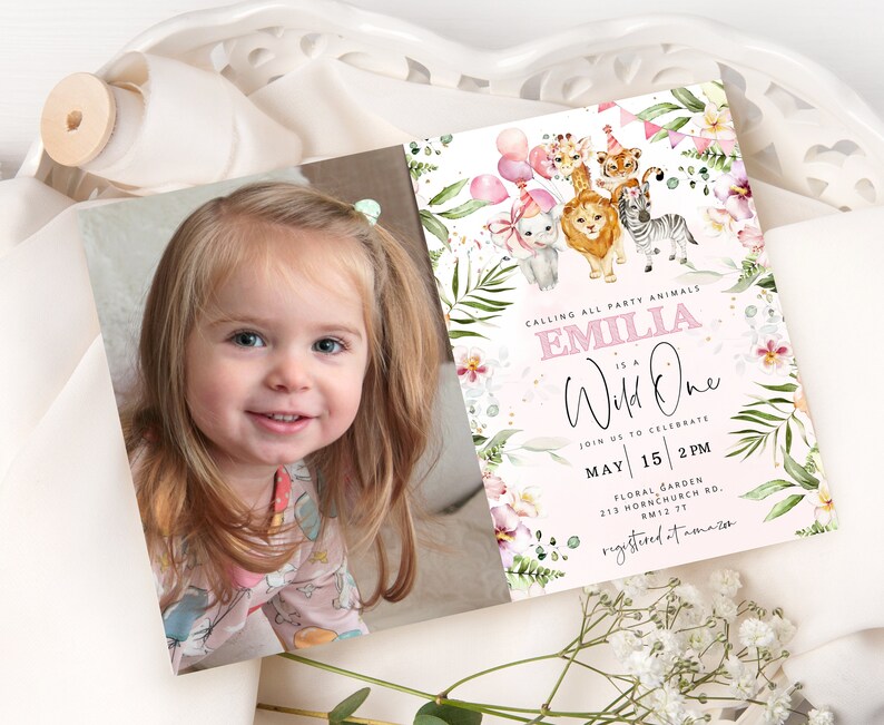 Op de afbeelding: Een roze en groene verjaardagsuitnodiging met een foto van een jong meisje. De uitnodiging luidt "Calling all party animals, Emilia is a Wild One. Join us to celebrate May 15, 2 PM. Floral Garden, 213 Hornchurch Rd, AM12 77. Registered at Amazon."