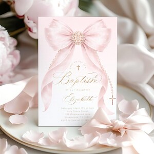 Può includere: Un biglietto d'invito per il battesimo con uno sfondo sfumato rosa tenue. La carta presenta un grande fiocco elegante con un centro gioiello e nastri fluenti. La scritta dorata recita "Battesimo" e "Elizabeth".