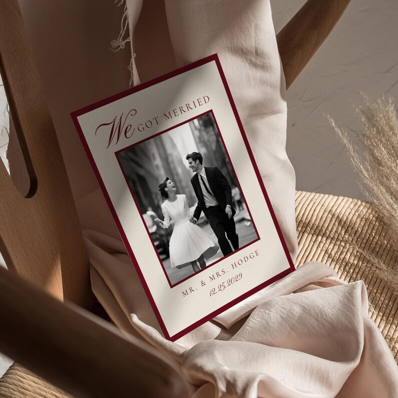 May include: A wedding invitation featuring a monochrome photograph of a couple. The invitation has a cream-coloured background with a claret border. Text includes "We Got Married", the couple's names, and the wedding date.