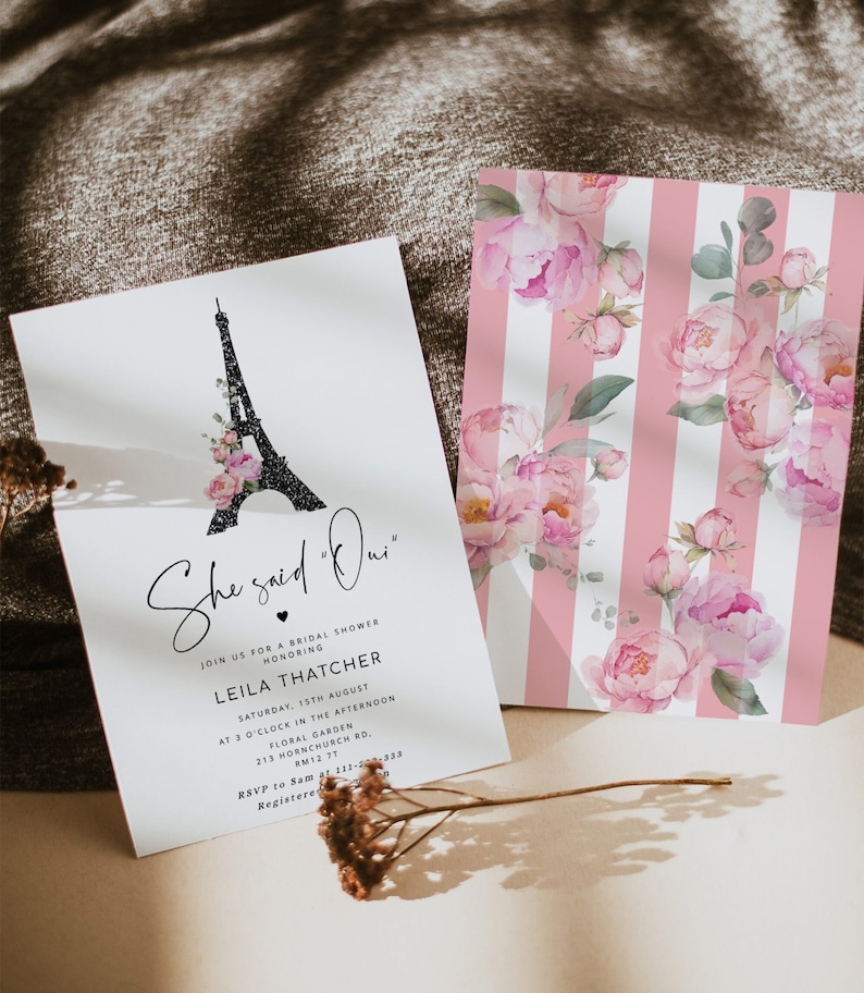 May include: A white invitation card with black text and a black and white illustration of the Eiffel Tower with pink flowers. The text reads "She said "Oui" Join us for a bridal shower honoring Leila Thatcher Saturday, 15th August at 3 o'clock in the afternoon Floral Garden 213 Hornchurch Rd, RM12 77 RSVP to Sam at 123-456-7890 Registered at ..."