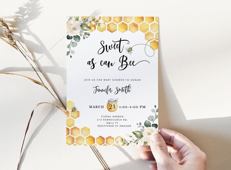 May include: A baby shower invitation with a watercolor illustration of a honeycomb, white flowers, and green leaves. The text reads "Sweet as can Bee" and includes the date, time, and location of the event. The invitation is for Jennifer Smith.
