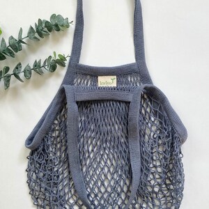 A gray cotton mesh bag with thick cotton straps. The bag is made with natural cotton and heavy duty mesh netting.