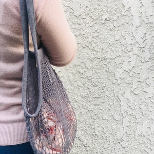 woman with a gray mesh bag on her shoulder