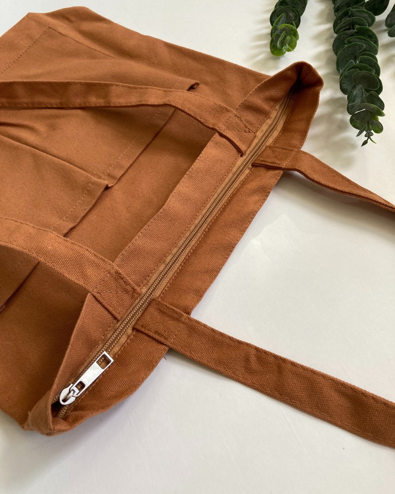 Brown work tote bag with zipper and pockets and shoulder straps.