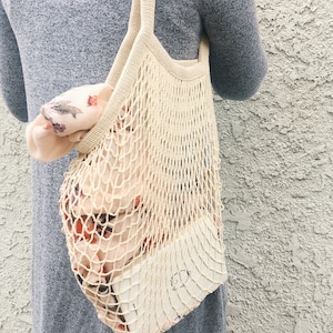lady wearing on her shoulder a beige cotton mesh bag with planner & scarf inside the bag