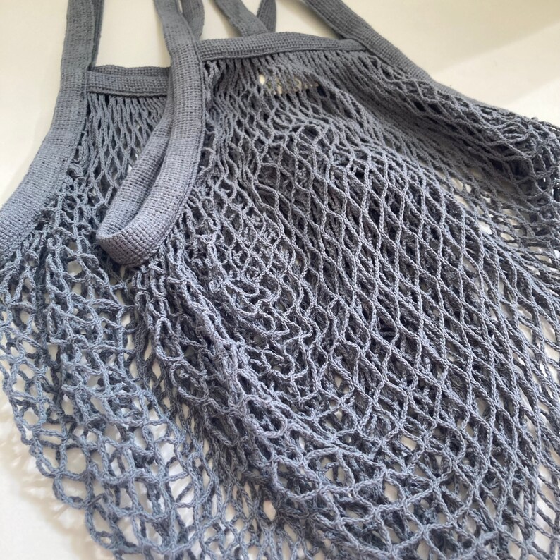 Set of gray string mesh bag with long durable handles. The reusable bag is made of a fine, tightly woven mesh that expands.