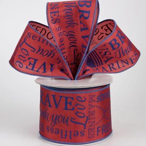 May include: Red ribbon spool with blue text that reads "Brave", "Thank you", "Love", and "Marines". The ribbon has a blue border and is arranged in a decorative bow.