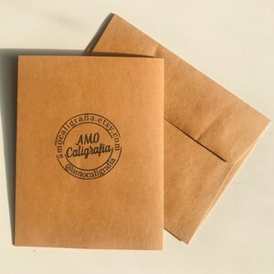 Pu&ograve; includere: Una busta di carta marrone con un logo circolare che dice "AMO Calligrafia" e "amocalligrafia.etsy.com" in testo nero.