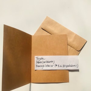 Pu&ograve; includere: Un biglietto marrone con una busta bianca. Il biglietto ha una nota scritta a mano che dice "Tarjeta Sobre (en blanco) Mensaje Interior (*1 a 20 palabras)"