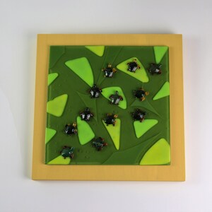 Può includere: Un'opera d'arte incorniciata quadrata con uno sfondo a mosaico di vetro verde e giallo. Il mosaico presenta uno schema di triangoli e piccole tartarughe marine di vetro nero e verde.