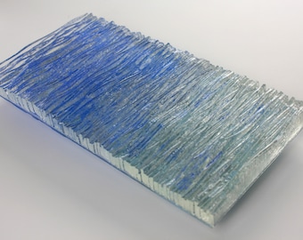 Könnte beinhalten: Ein rechteckiges Stück strukturiertes Glas mit einem blauen und weißen Farbverlauf. Das Glas hat ein welliges, gewelltes Muster.