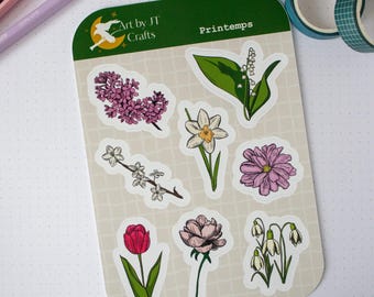 May include: A sticker sheet featuring various floral illustrations, including a tulip, lilac, and daffodil. The sheet has a green border with the text "Printemps" and the logo "Art by JT Crafts". The stickers are on a light beige background.