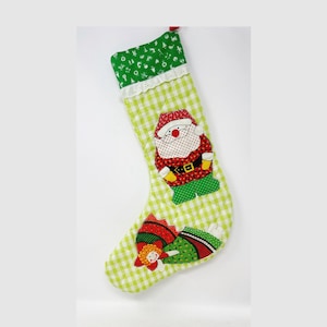 May include: Green and white checkered Christmas stocking with a Santa Claus and a Christmas tree applique.