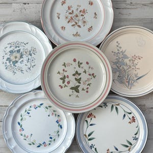 May include: A white ceramic mug with a black handle and the text "But First, Coffee" in a bold, black font. The mug is set against a neutral background, highlighting its simple design.