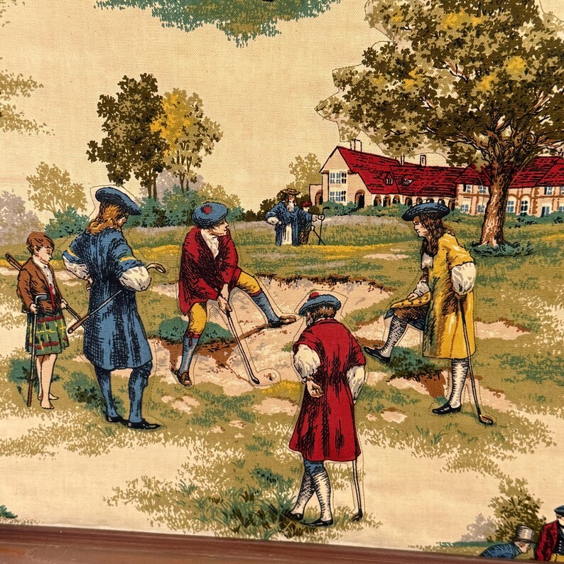 May include: A vintage fabric panel featuring a golf scene with figures in period clothing. The panel depicts a golf course with players in red, blue, and yellow coats, and a house in the background. The color palette includes green, beige, and brown.