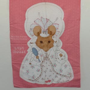 May include: A pink fabric panel featuring a cartoon mouse dressed in a bonnet and gown, holding a mirror. The text "Beatrix Potter Nursery Classics" and "Lady Mouse" are printed on the fabric. The design is outlined with stitching lines, and the words "Leave Open For Stuffing" are printed at the bottom.