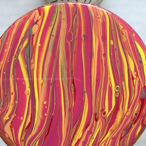 Könnte beinhalten: Ein runder Untersetzer in Pink, Gelb und Orange mit einem marmorierten, wirbelnden Design.