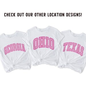 May include: Three white t-shirts with pink text. The shirts say "Georgia", "Ohio", and "Texas".