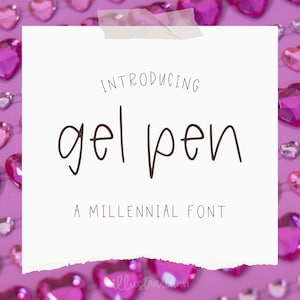May include: A white paper with the words "INTRODUCING gel pen A MILLENNIAL FONT" in brown lettering is taped to a purple background. The background is decorated with pink heart-shaped gems.