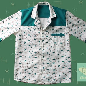 Könnte beinhalten: Ein weißes, kurzärmeliges Hemd mit Knöpfen, einem türkisfarbenen Kragen und einer Passe. Das Hemd hat ein geometrisches Muster aus weißen, türkisfarbenen und roten Sternen und Rauten. Das Hemd hat eine türkisfarbene Tasche auf der linken Seite.