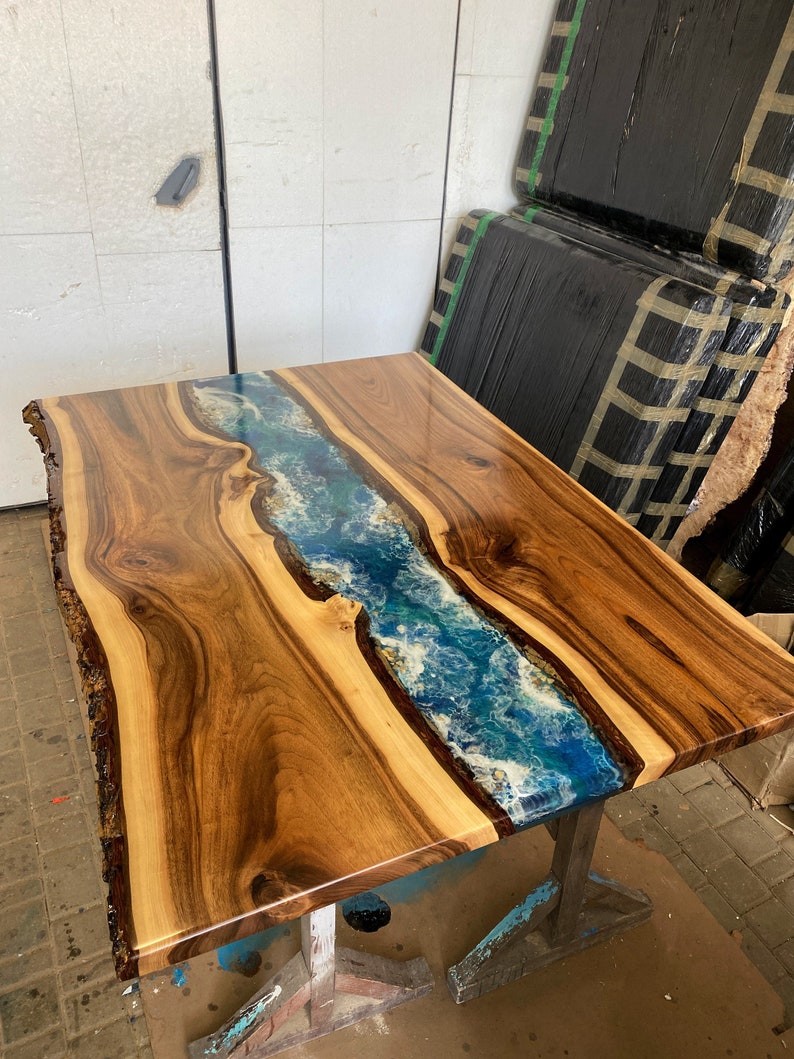 May include: A wooden table top with a live edge and a blue and white epoxy river running down the center.