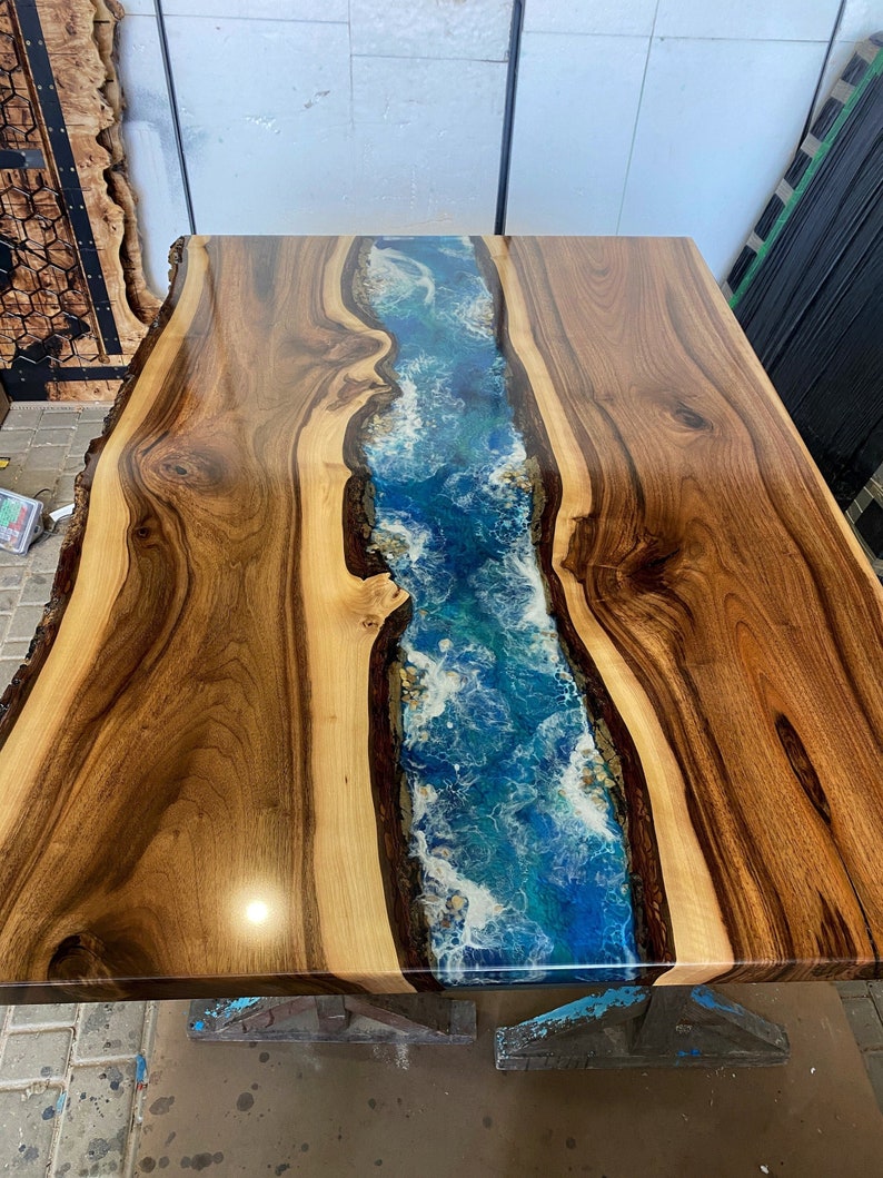 May include: A wooden table top with a blue and white resin river running down the center. The wood is a rich brown color and the resin is clear and glossy.