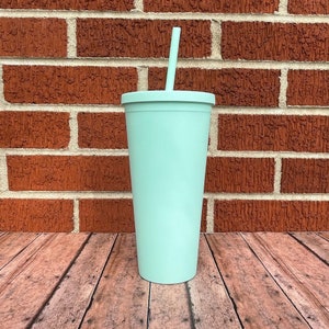 May include: A light blue reusable tumbler with a straw. The tumbler is made of stainless steel and has a matte finish.