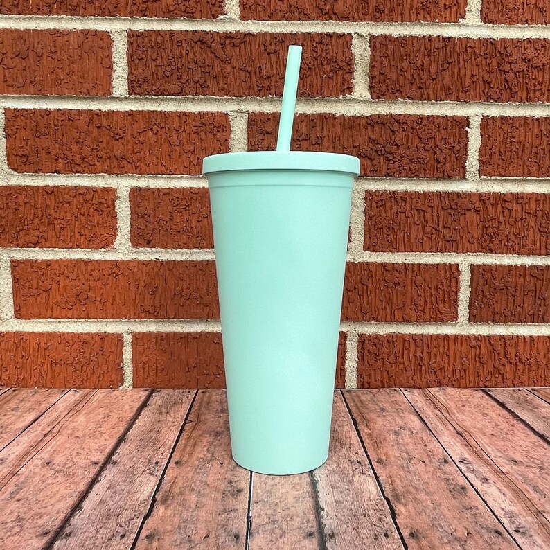 May include: A light blue reusable tumbler with a straw. The tumbler is made of stainless steel and has a matte finish.