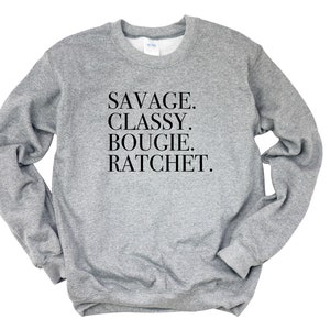 May include: Gray sweatshirt with the text "SAVAGE. CLASSY. BOUGIE. RATCHET." printed in black.
