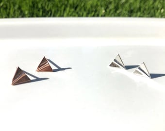 May include: Two pairs of earrings, one pair is silver and the other is rose gold. Both pairs are shaped like paper airplanes.