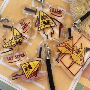 May include: Four yellow triangle-shaped keychains with black eyes and red outlines. The keychains feature different phrases, including "Hey There", "Hey Sixer", and "Yellow?"