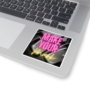 May include: A sticker with a black and white graffiti background and the words "MAKE YOUR mark" in pink and yellow neon lettering.