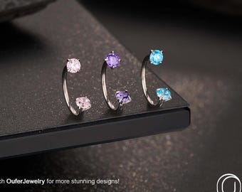May include: Three silver body jewelry pieces with colorful gemstones. The jewelry features a curved design with a gemstone at each end. The gemstones are pink, purple, and blue. The text "Search OuferJewelry for more stunning designs!" is visible.