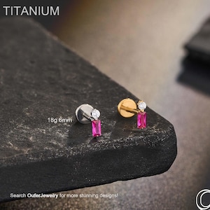 May include: Two titanium body jewelry pieces. One is silver-toned, the other gold-toned. Each features a small, clear gem and a rectangular, pink gemstone. The text "TITANIUM" is at the top. The text "18g 6mm" is also visible. The text "Search OuferJewelry for more stunning designs!" is at the bottom.