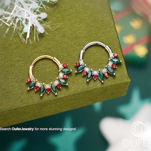 May include: Two hoop earrings, one gold and one silver, each decorated with green and red gemstones. The earrings are set against a green background with a snowflake and text that reads "Search OuferJewelry for more stunning designs!"