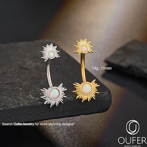 Puede incluir: Dos piercings para el ombligo, uno plateado y otro dorado, cada uno con un diseño de sol y una piedra central similar a un ópalo. El anillo dorado está marcado como 14g, 10mm. La imagen incluye el texto "Search OuferJewelry for more stunning designs!"