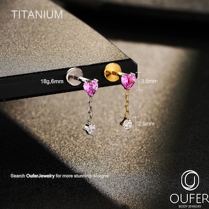 May include: Two titanium body jewelry earrings. One is silver-toned, the other gold-toned. Each features a pink heart-shaped gem, a chain, and a small, clear gem. The earrings are 3.5mm and 2.5mm in length. The text "TITANIUM" and "18g,6mm" are visible.