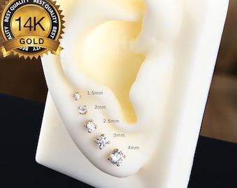 May include: A close-up of a model's ear with five different sizes of 14k gold ear studs with clear cubic zirconia stones. The sizes are 1.5mm, 2mm, 2.5mm, 3mm, and 4mm.