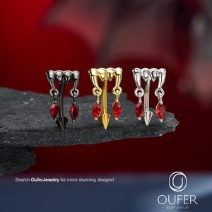 Könnte beinhalten: Drei gebogene Barbell-Piercings in Schwarz, Gold und Silber. Jedes Stück zeigt ein Vampirzahn-Design mit zwei hängenden, marquise-geschliffenen roten Edelsteinen. Der Text "Search OuferJewelry for more stunning designs!" und das Oufer-Logo sind zu sehen.