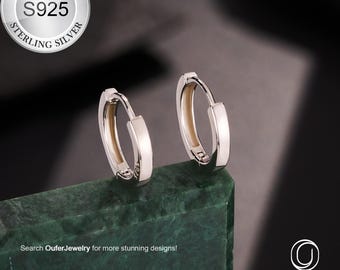 May include: A pair of sterling silver hoop earrings with a polished finish. The earrings are displayed on a green surface against a dark background. The image includes the text "STERLING SILVER S925 STERLING SILVER" and "Search OuferJewelry for more stunning designs!"