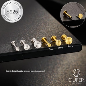 May include: A collection of silver and gold-colored body jewelry studs. The studs are displayed in a row, with sizes ranging from 2mm to 4mm. The image includes a close-up of a stud and the text "Search OuferJewelry for more stunning designs!"