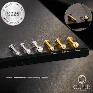 May include: A collection of body jewelry studs in silver and gold tones. The image includes a close-up of the studs, with sizes ranging from 2mm to 3mm. The text "STERLING SILVER S925" is visible, along with the brand name "OUFER BODY JEWELRY".