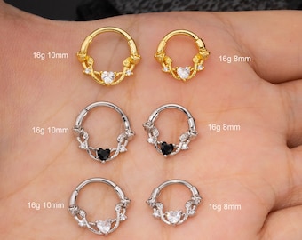 Puede incluir: Tres pares de anillos de clic sin costuras de calibre 16 con un diseño floral y un corazón en el centro. Los anillos están disponibles en oro, plata con corazón negro y plata con corazón transparente. Los anillos tienen un diámetro de 8 mm y 10 mm.